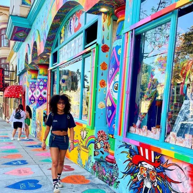 女人走在海特街，背景是一幅彩色的壁画.