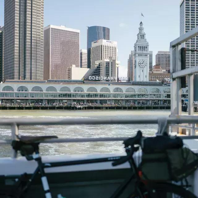自行车靠在栏杆上，背景是渡轮大楼.